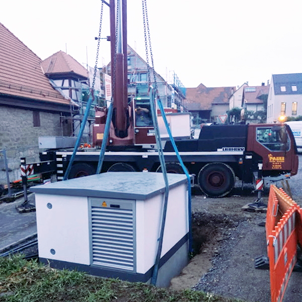 Kran setzt großen Schaltschrank auf der Baustelle